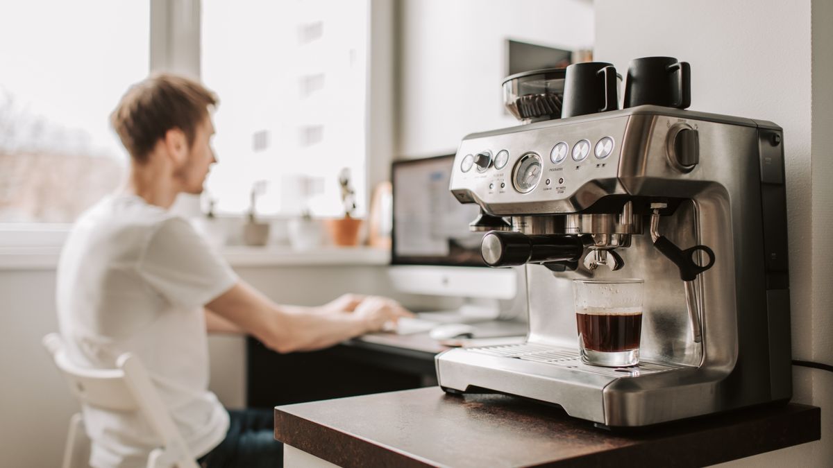 A coffee machine for office use on a worktop beside a desk