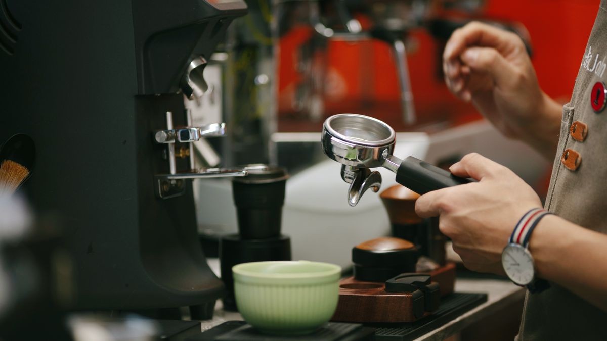 A barista grinding fresh coffee into a portafilter