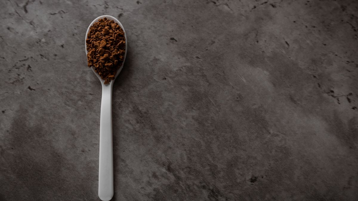 A spoonful of freeze dried coffee granules on a dark surface