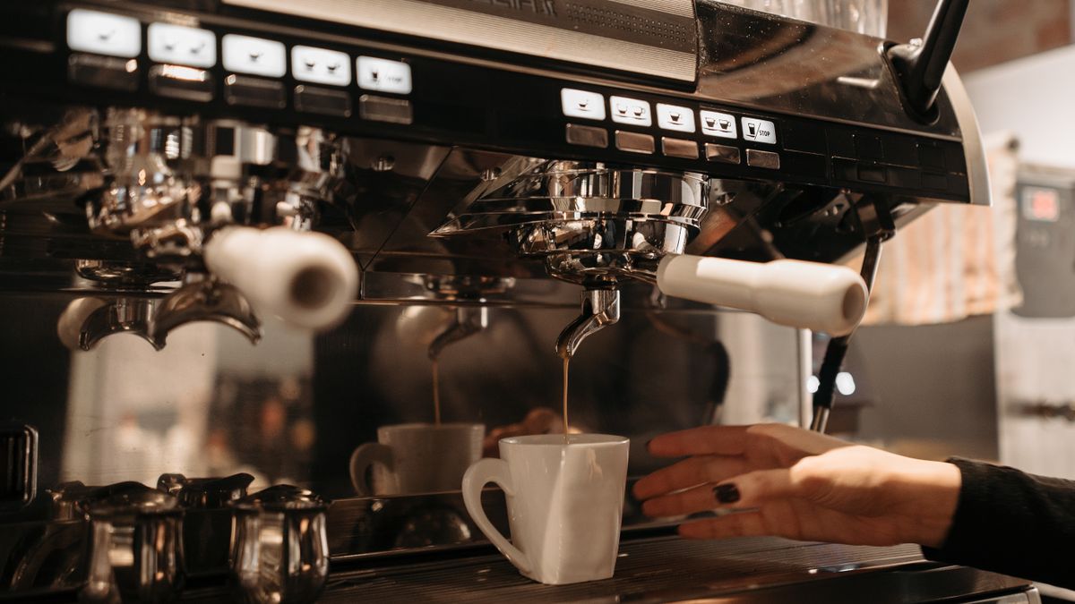 A barista using a commercial coffee machine in a cafe